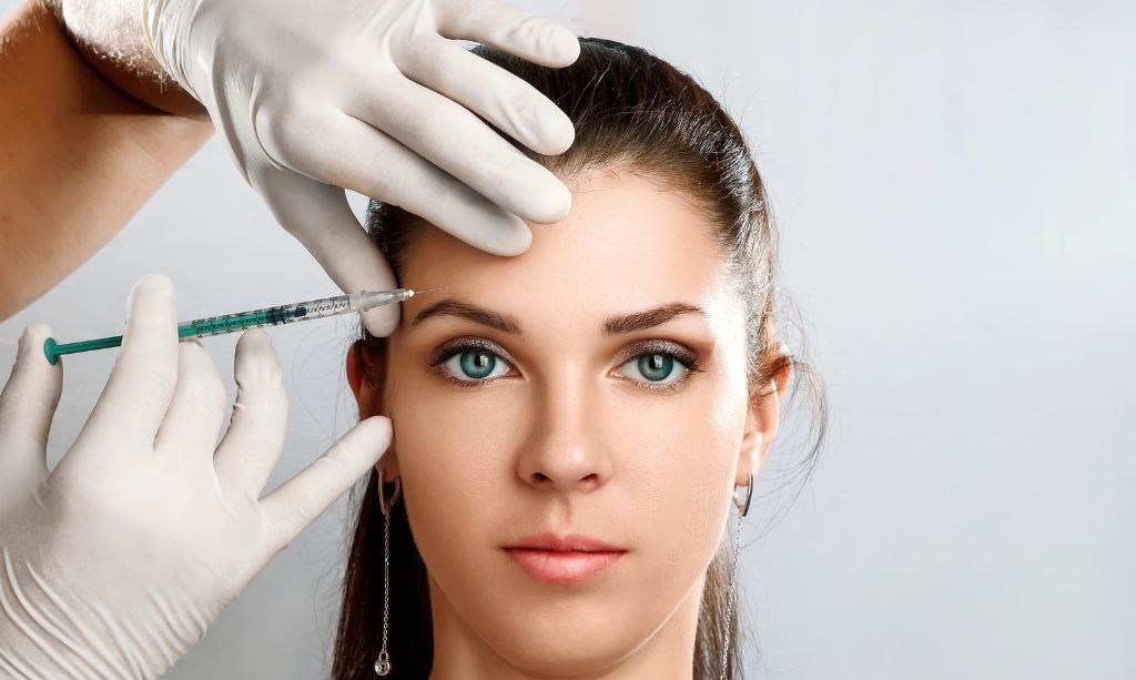 Unidentified master cosmetologist makes botox injections into the eyebrow of a beautiful young woman client. The concept of rejuvenating aesthetic procedures | The Skin Refinery in Fayetteville, TN