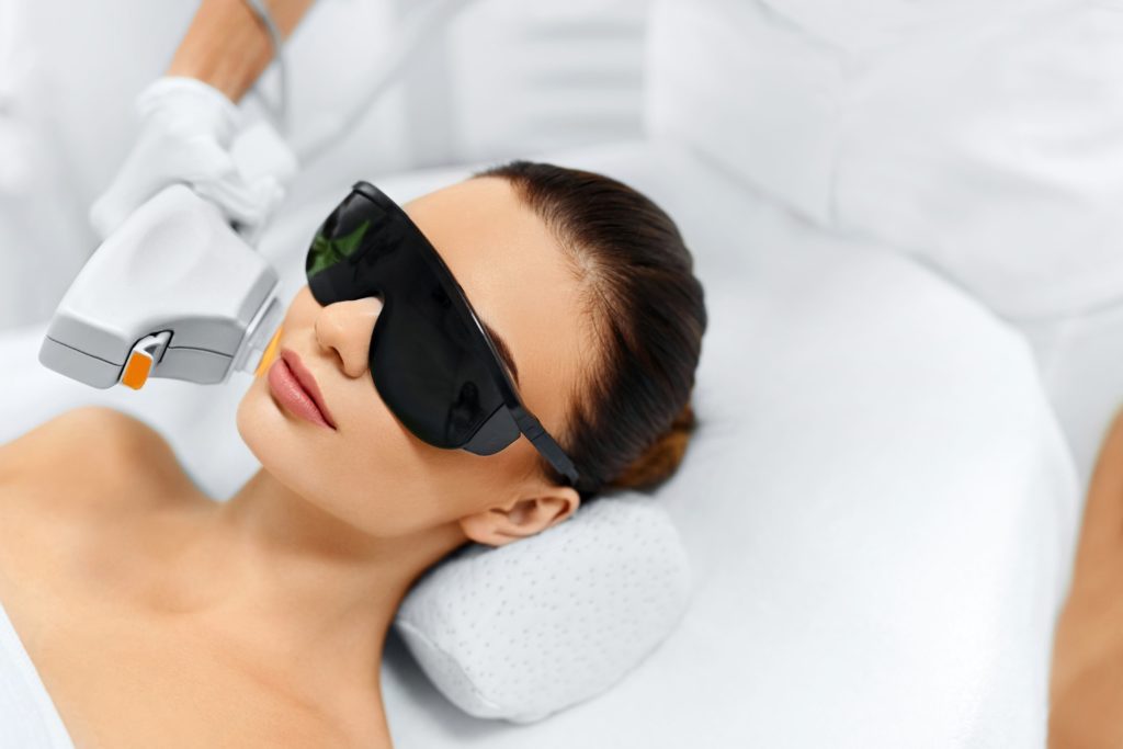 Young Lying Woman Wearing Safety Goggles & Getting Laser Treatment | The Skin Refinery in Fayetteville, TN